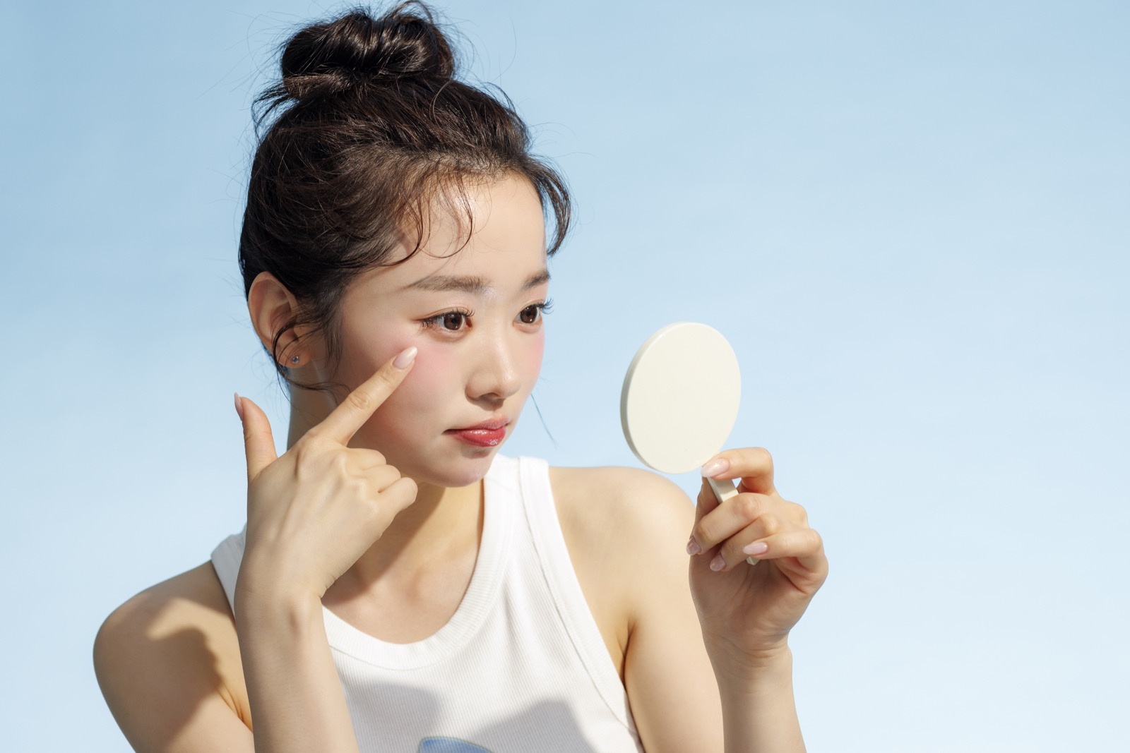 손거울을 보며 광대 부위 기미를 살피는 여성