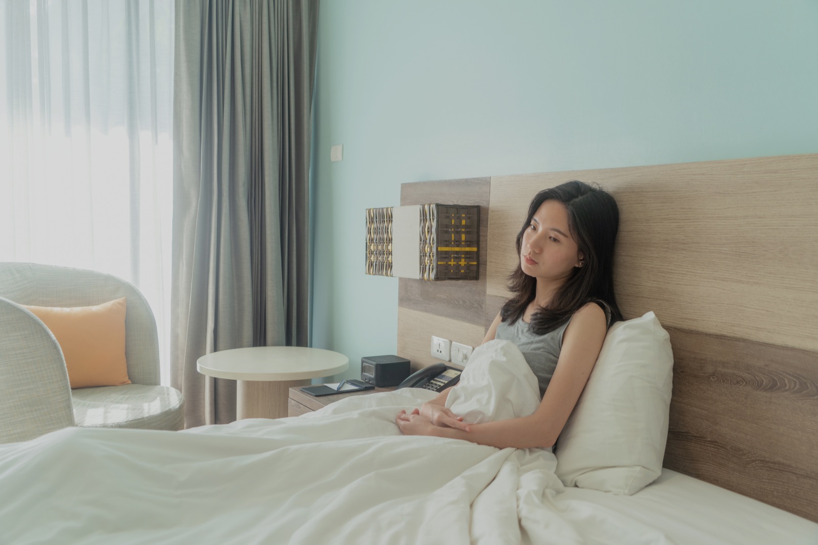 아침에 일어나 침대에 앉아 멍한 표정을 짓는 여성