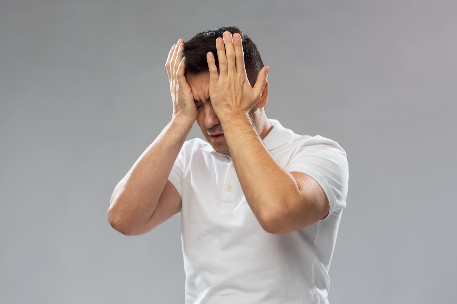 심한 두통으로 머리를 양손으로 감싸 쥔 남성