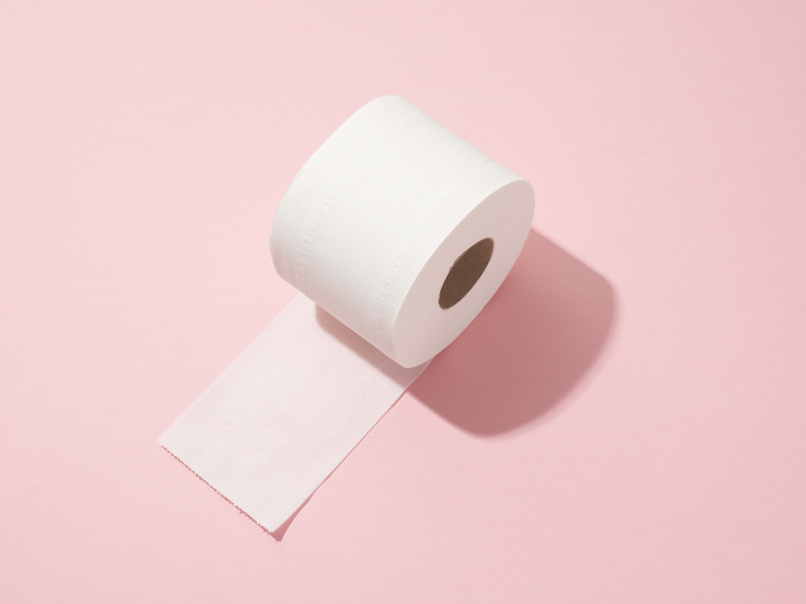 분홍 배경 위에 놓인 두루마리 휴지